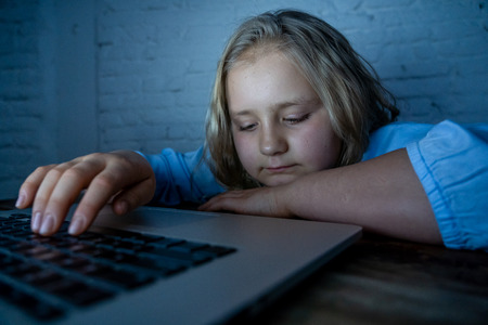 Scared sad girl bullied on line with laptop suffering cyber bullying harassment feeling desperate and intimidated. Child victim of bullying stalker social media network and the dangers of internet.の写真素材