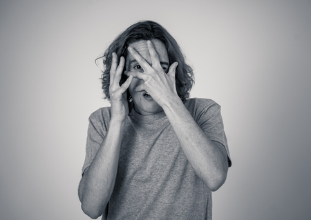 Young man feeling frightened and shocked making scared gestures in fear and anxiety. Terrified desperate teenager trying to cover himself from an aggression. People expressions and youth violence.の写真素材