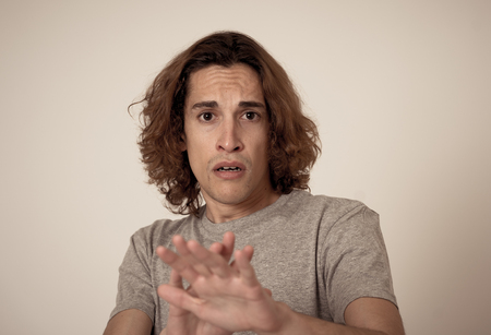 Young man feeling frightened and shocked making scared gestures in fear and anxiety. Terrified desperate teenager trying to cover himself from an aggression. People expressions and youth violence.の写真素材