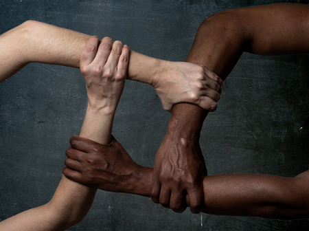 Races united against discrimination and racism. Black African American and Caucasian hands holding together in world unity and racial love and understanding. Tolerance and cooperation concept.の写真素材