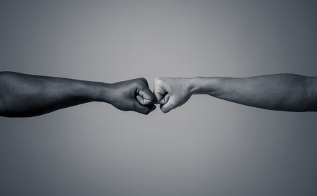 Black African American race male and white Caucasian woman hands giving a fist bump in agreement partnership and cooperation multiracial diversity and immigration concept. Stop racism campaign.の写真素材