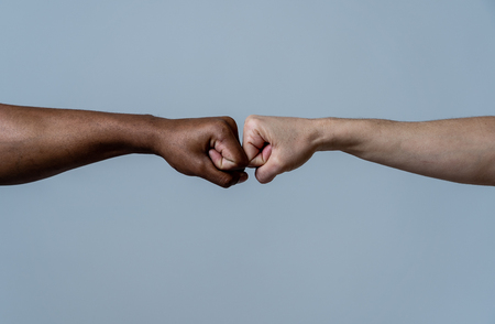 Black African American race male and white Caucasian woman hands giving a fist bump in agreement partnership and cooperation multiracial diversity and immigration concept. Stop racism campaign.の写真素材