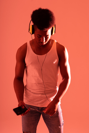 Artistic portrait of strong african american young dancer or DJ with headphones ready to play or dance in disco dance floor neon light in Internet Music festival and online music technology concept.の写真素材