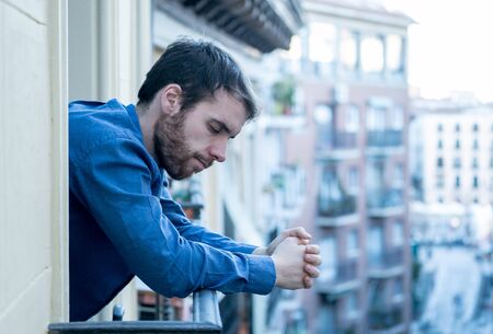 Lonely sad man staring outside house balcony feeling depressed distress and miserable. Suffering emotional crisis thinking about difficult important life decision In Men Depression and mental health.の写真素材