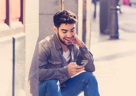 Fashion college man in his twenties happy checking blog or chatting on the internet with friends on...