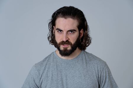Portrait of angry and upset young hipster man looking furious, aggressive and crazy in People and human emotions, facial expressions and abuse, violence and bullying concept. Isolated on neutral.の写真素材