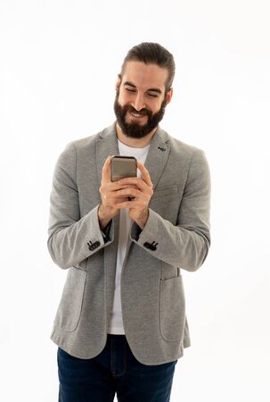 Portrait of handsome successful hipster emailing and sending messages on mobile smartphone or on social media network isolated on white background. In People Internet Communication and technology.の写真素材