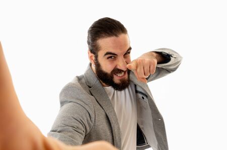 Young attractive hipster man holding camera or smartphone mobile shooting selfie or recording video for his followers. In Technology, internet social media network and blogging business concept.の写真素材