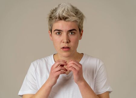Portrait of young scared teenager man in shock making frightened gestures. Transgender teen...