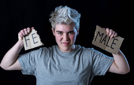 Handsome transgender teenager tearing the word Female into MALE in Gender identity, equality and human rights. Breaking silence about own gender identity transgender Pride and freedom concept.の写真素材