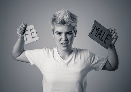 Handsome transgender teenager tearing the word Female into MALE in Gender identity, equality and...