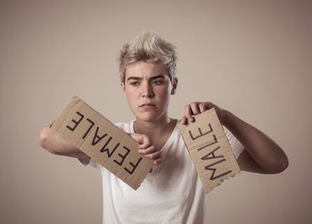 Handsome transgender teenager tearing the word Female into MALE in Gender identity, equality and human rights. Breaking silence about own gender identity transgender Pride and freedom concept.の写真素材
