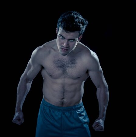 Portrait of strong muscular sports man with an intense furious look. Expressive sexy shirtless angry man looking powerful on black background in Workout, training and fitness concept.の写真素材