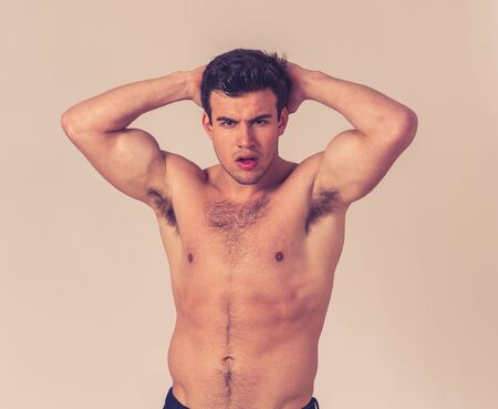 Portrait of sexy handsome Athletic man with strong torso posing manly for the camera. Studio shot of...