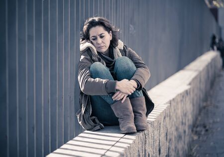 Young adult felling shame depressed and hopeless sitting alone in city urban street in Depression Loneliness Mental health Emotional pain Social violence Abusive relationship and Harassment concept.の写真素材