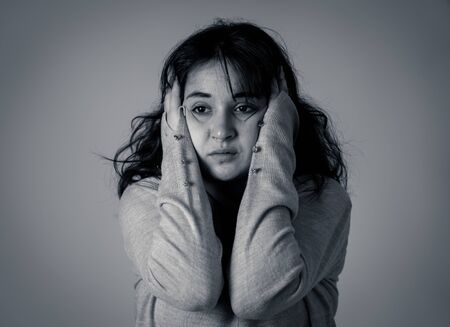 Close up portrait of beautiful young woman with sad eyes looking desperate and melancholy. Human facial expressions and emotions, depression and mental health concept. Isolated on dramatic background.の写真素材