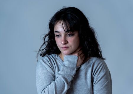 Close up portrait of beautiful young woman with sad eyes looking desperate and melancholy. Human facial expressions and emotions, depression and mental health concept. Isolated on dramatic background.の写真素材