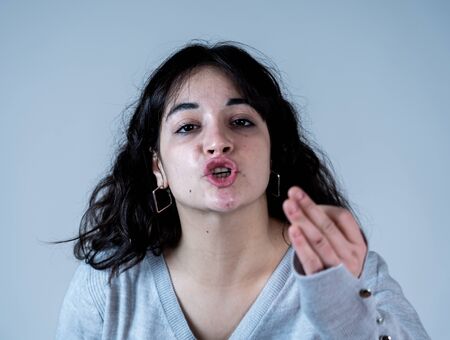 Facial expressions and emotions. Close up portrait of Young attractive hispanic woman with an angry face. Looking mad and crazy shouting and making furious gestures. Isolated on moody background.の写真素材