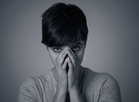 Black and white portrait of beautiful young woman looking sad and stressed, her head resting on her...