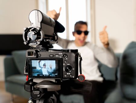Close up image of camera screen on tripod recording a video blog with blurred Young happy man on his...