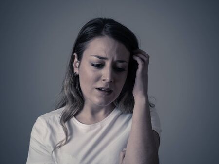 Close up portrait of beautiful young woman with sad mood looking miserable and melancholy. Human facial expressions and emotions, depression and mental health concept. Isolated on neutral background.の写真素材