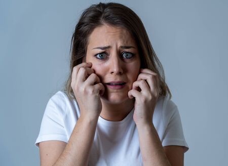 Close up of young woman feeling scared and shocked making fear, anxiety gestures. Looking terrified and desperate. People and Human expressions and emotions concept. Isolated on neutral background.の写真素材
