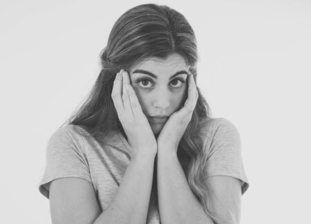 Close up in black and white of young woman feeling afraid and shocked hiding her face from something scary. Looking with fear in her eyes. People and Human expressions and emotions. With copy space.の写真素材