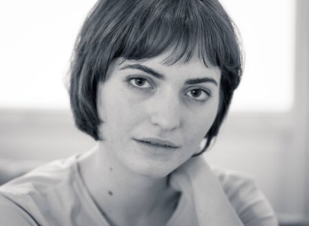 Black and white portrait of young beautiful woman with happy face, beautiful smile and bob haircut. Sitting on sofa staring at the camera. In beauty, model and lifestyle concept.の写真素材
