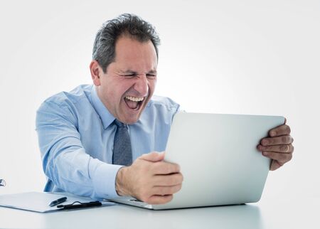 Angry and frustrated middle aged businessman overworked at desk upset with laptop in adults perception and use of technology, Overtime, stress at work concept isolated in white background.の写真素材