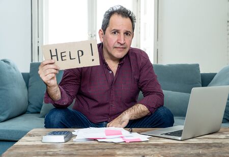 Worried and desperate mature man asking for help in paying off debts and loan calculating bills tax expenses and accounting home finances on couch in Domestic bills and Financial problems concept.の写真素材