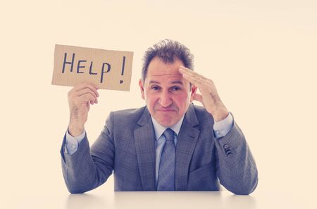 Depressed middle aged caucasian businessman desperate and tired holding a help sign looking...