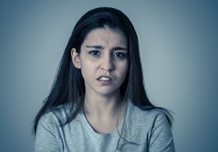 Close up of a young sad woman, serious and concerned, looking worried and thoughtful. Feeling sorrow and depression. With copy space. In facial expressions and human emotions concept.の写真素材