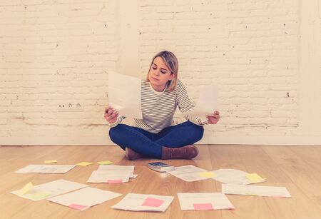 Portrait of worried young woman feeling stressed and desperate on the ground with calculator...