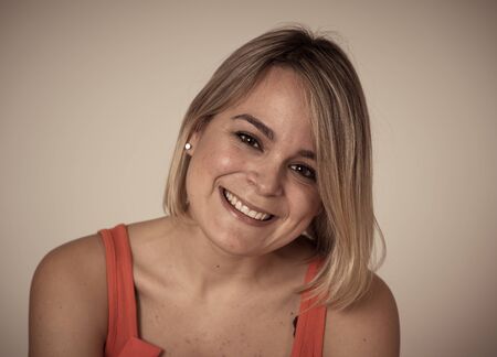 Head shot portrait of young attractive caucasian woman with blond hair and beautiful smile and harming face expression. Feeling confident posing and modeling. In lifestyle and beauty concept.の写真素材