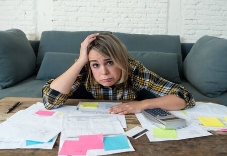 Portrait of worried and desperate young entrepreneur woman accounting home or small business finances feeling stressed not able to pay off debts, bills, rent and expenses. In financial problems.の写真素材