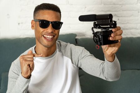 Life style portrait of young happy male blogger on camera screen filming a video tutorial for the...