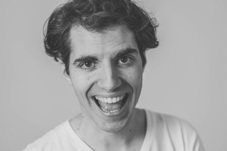 Close up portrait of happy young caucasian latin man wearing white T-shirt. Smiling feeling...