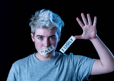 Handsome transgender teen with mouth sealed with male and female word written in Tape. Conceptual...