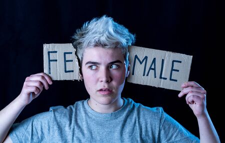 Handsome transgender teenager tearing the word Female into MALE in Gender identity, equality and human rights. Breaking silence about own gender identity transgender Pride and freedom concept.の写真素材