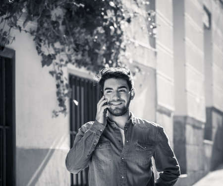 Young happy man in his twenties on mobile phone talking and chatting with friends on social media app on holidays in Europe. In communication, Traveling, technology internet and lifestyle concept.の写真素材