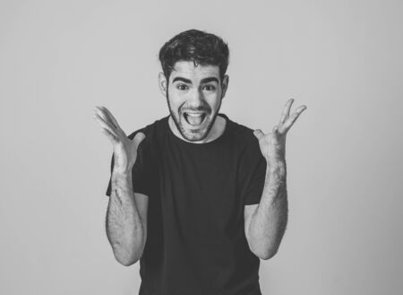 Portrait of a handsome latin young man surprised and shocked hearing great news. Attractive male looking amazed with wide eyes and mouth open in surprise. Human facial expressions and emotions.の写真素材