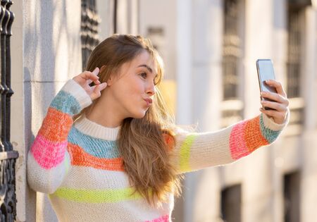 Pretty teenager girl taking selfie happy and excited in the city. Young student woman recording video of herself blogging outdoors In Millennial generation Connections Technology and Online trends.の写真素材