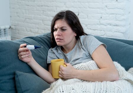 Health care and medicine. Sick woman lying on sofa at home unwell with headache sore nose checking...