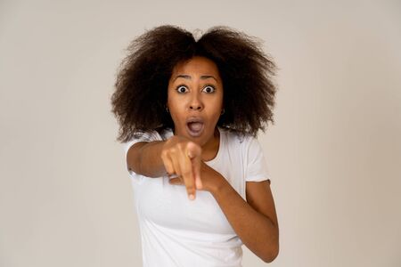Beautiful shocked african american woman looking and pointing at something unbelievable or having great success with surprised and happy face and gestures. In People and human emotions and expressions.の写真素材