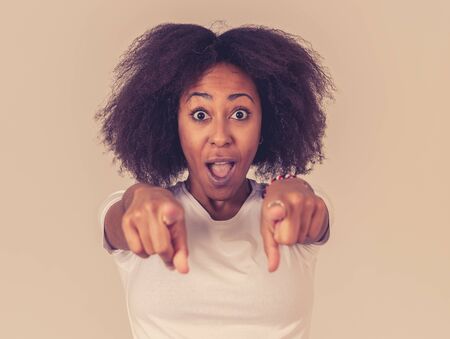 Beautiful shocked african american woman looking and pointing at something unbelievable or having great success with surprised and happy face and gestures. In People and human emotions and expressions.の写真素材