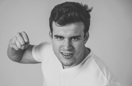 Young attractive man in rage looking furious in defence stance and threaten punching with fist in angry upset and mad face expression isolated grey background in youth violence and aggression concept.の写真素材