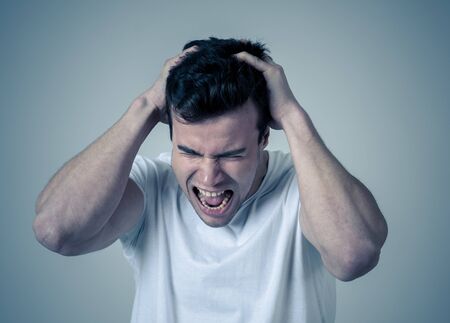 Portrait of a young sad latin man depressed and hopeless crying in emotional pain. Feeling sorrow and suicidal Isolated in neutral background. In People human emotions and mental health concept.の写真素材