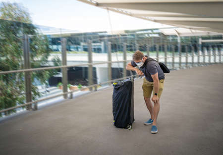 Coronavirus outbreak travel ban and restrictions. Traveler man with face mask at international airport affected by flight cancellation. COVID-19 pandemic and worldwide borders closures and shutdowns.の写真素材