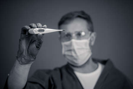 COVID-19 Outbreak visual support. Doctor holding thermometer. Protect yourself and prevent the spread of the coronavirus. If you have a fever, cough and difficulty breathing, seek medical attention.の写真素材