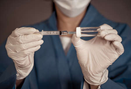 COVID-19 Coronavirus Vaccine. Doctor scientist with syringe analyzing virus Sars-CoV-2 in research...